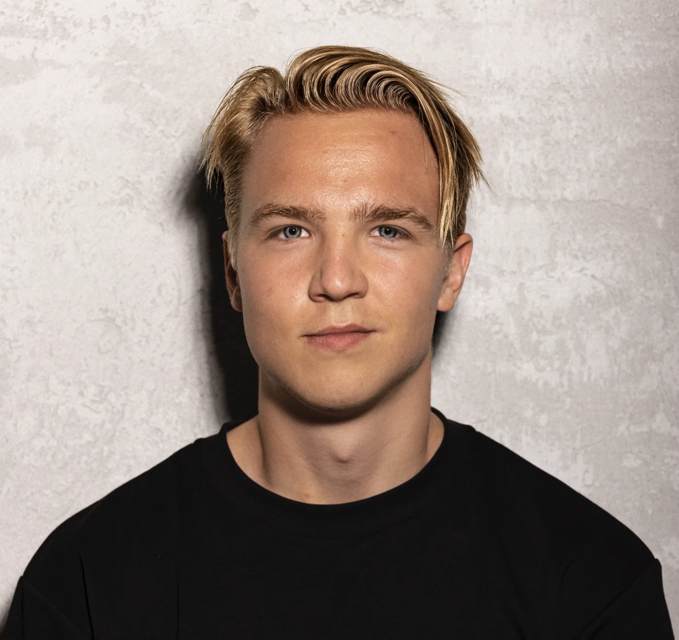 Portrait of Matias Myhrberg in a black t-shirt against a concrete wall